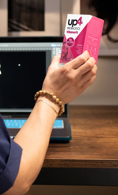 women's arm holding up a box of Up4 Women's Probiotics